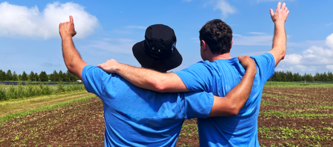 two men standing in a field pointing at the sky