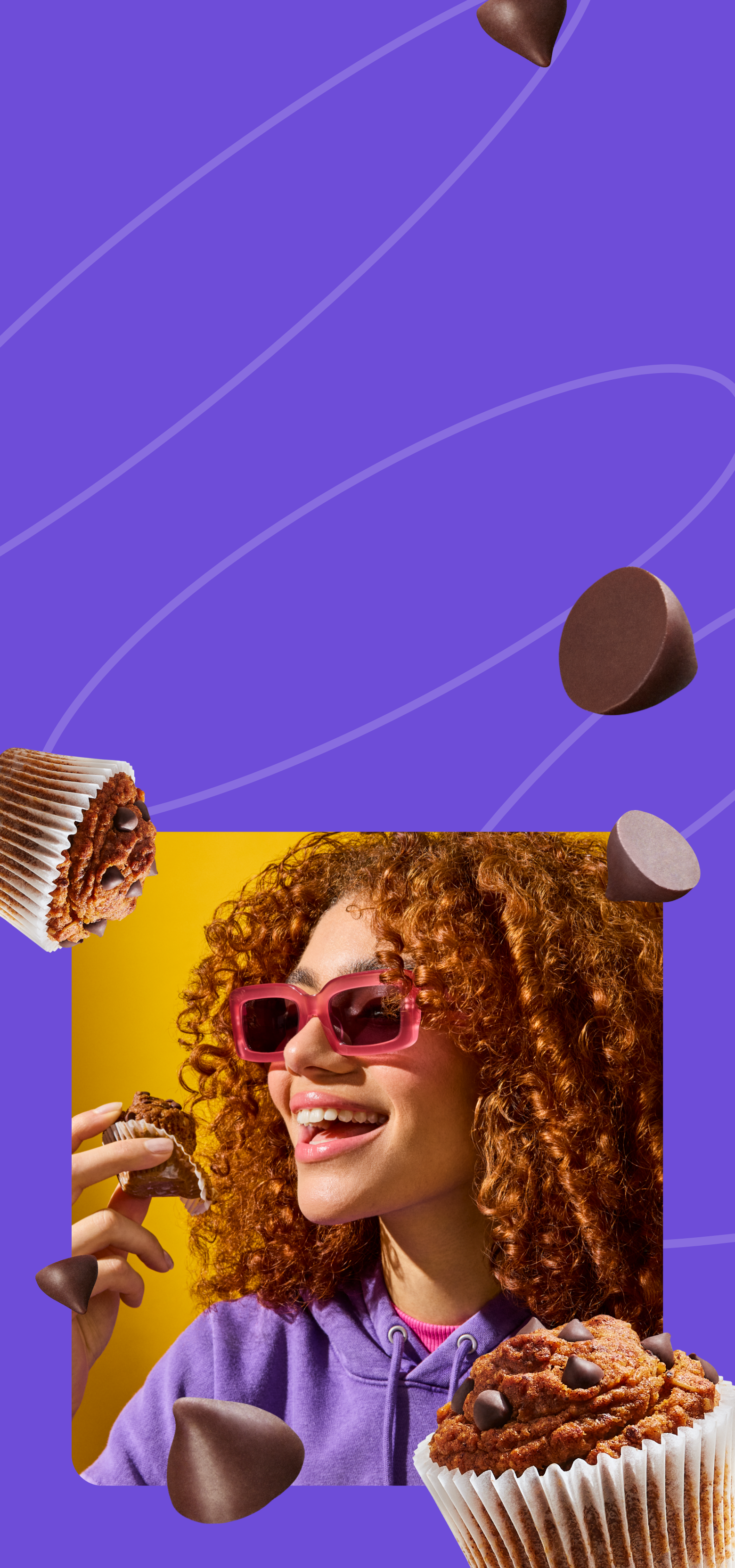 A young woman with voluminous curly red hair and pink sunglasses smiles as she holds a Mornings Oat Cup in a paper wrapper. She is wearing a purple hoodie and a pink turtleneck, with a bright yellow background adding vibrancy to the image. The scene exudes joy and indulgence.